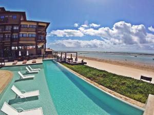 a hotel with a swimming pool next to a beach at Barra Bali - Luxo e Paraiso in Barra de São Miguel
