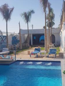 a swimming pool with two blue benches and palm trees at Moon Valley Apartments in Luxor
