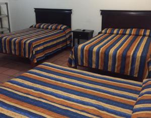 two beds with striped sheets in a hotel room at Hotel Ibiza in Veracruz