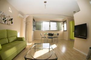 - un salon avec un canapé vert et une table dans l'établissement Apartamentos Loft Tarifa, à Tarifa