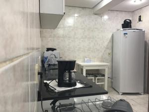 a kitchen with a sewing machine and a refrigerator at Avenida Residence in Uruguaiana