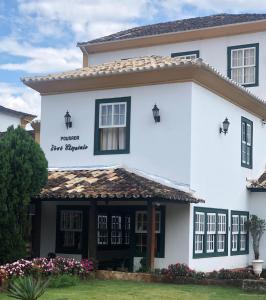 une maison blanche avec des fenêtres noires et un panneau indiquant la princesse de nouveaux moteurs dans l'établissement Pousada Vovô Chiquinho, à Tiradentes