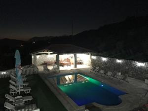 a swimming pool at night with chairs around it at Apartments Vila Lazarevic in Tivat