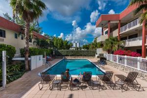 a person sitting in chairs next to a swimming pool at La Costa Beach Club in Pompano Beach