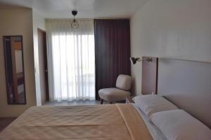 a bedroom with a bed and a chair and a window at Hotel El Sausalito in Ensenada