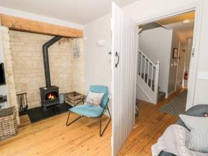a living room with a chair and a fireplace at Carp's Rise Cottage in Somerford Keynes