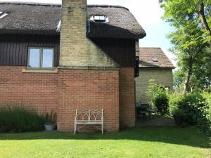 a brick house with a chimney and a window at Carp's Rise Cottage in Somerford Keynes