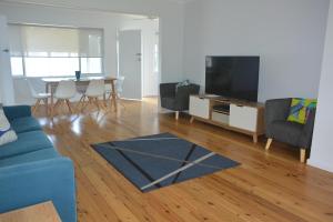 een woonkamer met een blauwe bank en een tv bij Glenrowan Erowal Bay in Erowal Bay