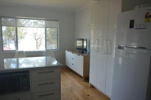 a kitchen with white cabinets and a refrigerator at Glenrowan Erowal Bay in Erowal Bay