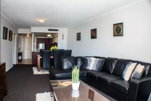 sala de estar con sofá de cuero negro y mesa en Deluxe Chevron Renaissance en Gold Coast