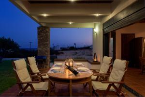 a wooden table and chairs on a patio at CRISTELIA SEAFRONT & POOL VILLA in Lakhania