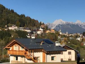 a house with a solar roof with mountains in the background at Chalet delle Dolomiti in Pieve di Cadore