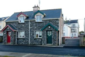 a stone house with a red door on a street at Ceol na Mara Holiday Homes - Cois Tra & Cor na dTonn in Enniscrone