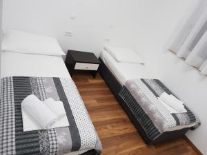 two twin beds in a room with a night stand at Apartmani Marija in Baška Voda