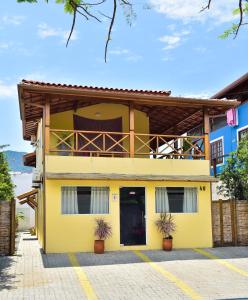 a yellow house with a balcony on top of it at Guaiamu Suítes Ilhabela in Ilhabela