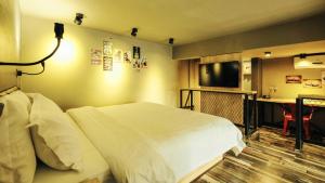 a hotel room with a bed and a flat screen tv at VIZ Culture & Arts Apartment in Nanning
