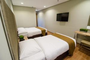 a hotel room with two beds and a flat screen tv at Madison Hotel PHL in Iloilo City