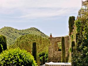 un antiguo edificio de piedra con árboles y montañas en el fondo en Hotel Scapolatiello, en Cava deʼ Tirreni