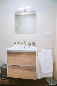 een badkamer met een wastafel en een klok aan de muur bij Lechartier Oporto apartments 1 in Porto