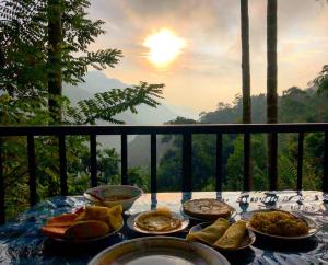 a table with plates of food on a balcony at adam's apple homestay in Ella