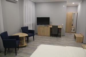阿斯塔纳Hotel Inju Hills的一间配有电视、椅子和桌子的等候室