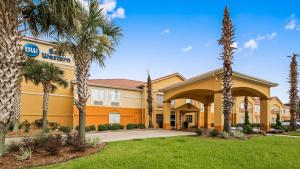 a hotel with palm trees in front of a building at Best Western Lafayette Inn in Lafayette