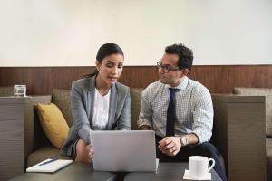 Ein Mann und eine Frau sitzen an einem Tisch mit einem Laptop in der Unterkunft Hyatt House Augusta Downtown in Augusta