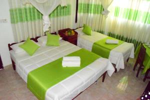 two beds in a room with green and white at Kandy Holiday Home in Kandy