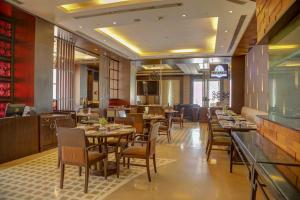 a restaurant with tables and chairs and a bar at Goldfinch Hotel Delhi NCR in Faridabad