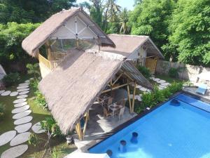 a house with a thatch roof and a swimming pool at Gili Matiki in Gili Islands