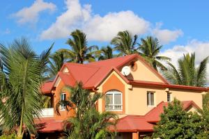 une maison avec un toit rouge et des palmiers dans l'établissement La Kazette - Votre Studio de Vacances à l Île de La Réunion, à Saint-Louis