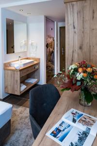 a bathroom with a sink and a table with a vase of flowers at Alpensporthotel Mutterberg in Mutterbergalm