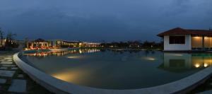 een groot zwembad 's nachts met verlichting aan bij K RESORT in Pondicherry