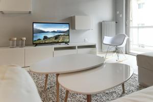 a white living room with a white table and a tv at Penelope's Luxury Apartment in Athens