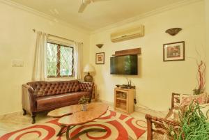 a living room with a leather couch and a tv at Villa Samaara9 Candolim Beach in Candolim