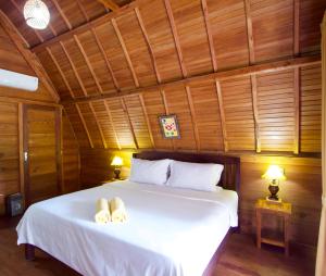 a bedroom with a white bed with two towels on it at Nusa Penida Pudak Nature Bungalow in Nusa Penida