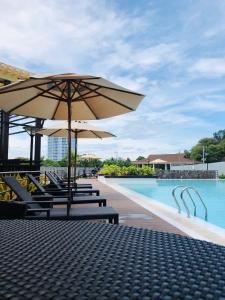- une piscine avec des chaises longues et des parasols à côté de la piscine dans l'établissement En Gee’s Crib, à Cagayán de Oro