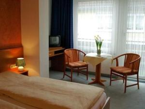 um quarto de hotel com uma cama, uma mesa e cadeiras em Hotel-Pension Ursula em Bad Sachsa