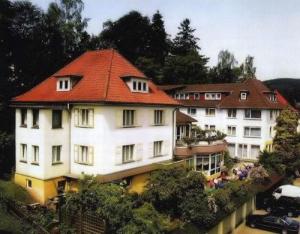 un gran edificio blanco con techo rojo en Hotel-Pension Ursula en Bad Sachsa