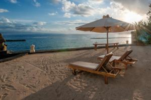 a beach with two chairs and an umbrella and the ocean at Orlowsky Discovery Candidasa Hotel in Candidasa