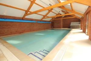an indoor swimming pool with a brick wall and wooden ceilings at Moulton-Barrett Barn in Bideford