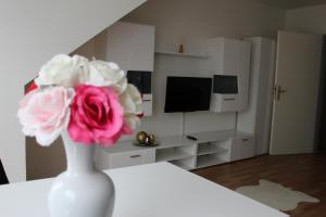 a white vase with a pink flower in a living room at ZV-Scholtz Burghausen, Mozartstr.15 AP-52 in Burghausen