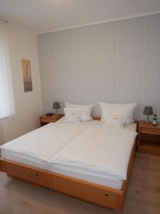 1 dormitorio con 1 cama grande con sábanas y almohadas blancas en Haus Nethegau en Bad Driburg