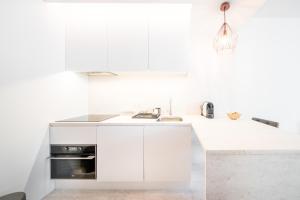 a white kitchen with a sink and a stove at Casa Chiado in Lisbon