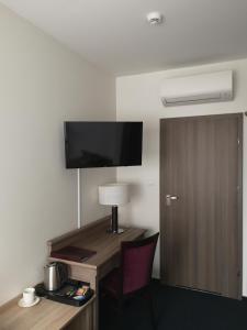 a hotel room with a desk and a tv on the wall at WILla Medica in Poznań