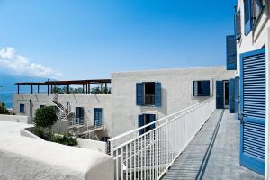 a white building with blue shutters and a balcony at NerOssidiana in Acquacalda