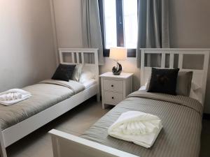 two twin beds in a room with a window at Noray Swan Duplex right at the Pool in Puerto Calero +22 photos