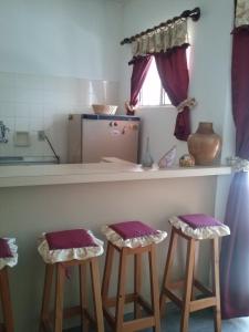 a kitchen with two bar stools with purple cushions at Recanto do descanso in Iguaba Grande