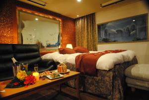 鈴鹿市にあるホテル マリオンのベッド、ソファ、テーブルが備わるホテルルームです。