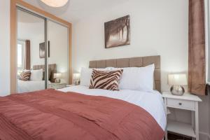 a bedroom with a large bed with a red blanket at Treetops Apartment in Milton Keynes